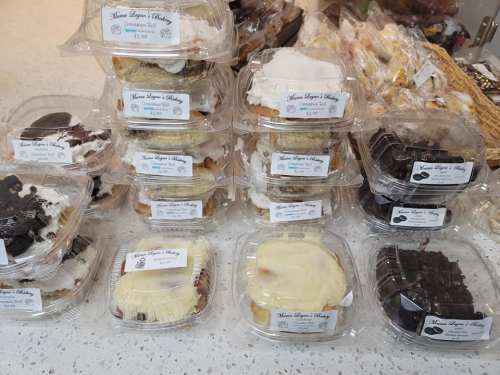 A display of assorted baked goods in clear containers, labeled with prices, on a countertop.