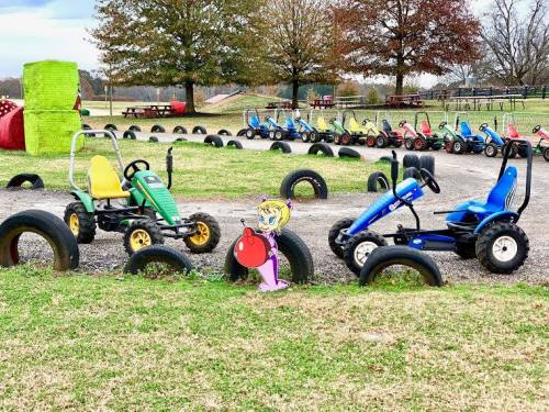 Go-karts lined up on a track with colorful tires, featuring a cartoon character holding a red balloon.