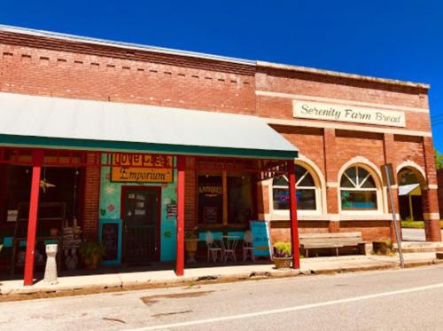 Quaint storefronts in a small town, featuring colorful signs and a clear blue sky above.