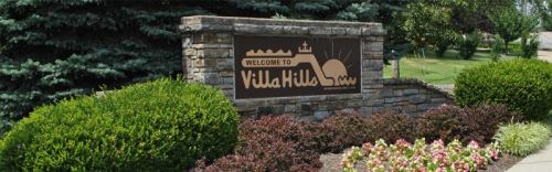 Welcome sign for Villa Hills, surrounded by greenery and colorful flowers.