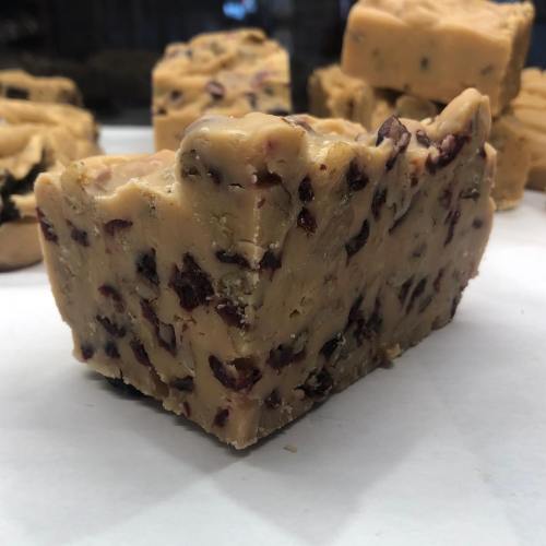 A close-up of a piece of soap with a creamy texture and visible cranberry pieces, set against a white background.