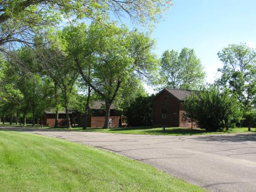 A peaceful street lined with trees and wooden houses under a clear blue sky.