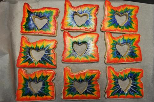 Colorful cookies shaped like the state of Oregon, each with a heart cutout in the center, arranged in a grid.
