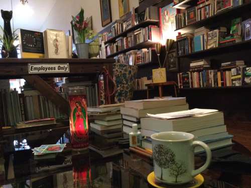 A cozy bookstore interior with shelves of books, a candle, a cup on a table, and a warm, inviting atmosphere.