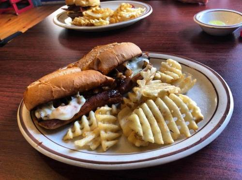A plate with two sandwiches and a side of waffle fries on a wooden table.