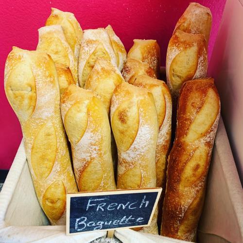 A basket of freshly baked French baguettes with a chalkboard sign labeled "French Baguette."
