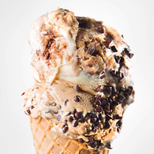 A close-up of a delicious ice cream cone topped with chocolate chips and swirls of creamy flavors.