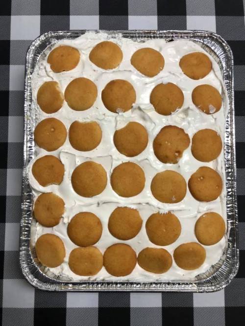 A tray of dessert featuring a creamy layer topped with round vanilla wafers on a checkered tablecloth.