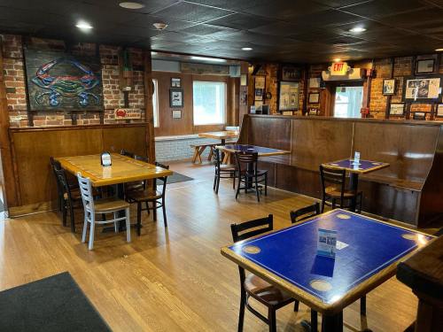 Interior of a casual restaurant featuring wooden tables, chairs, and brick walls with artwork. Bright and inviting atmosphere.