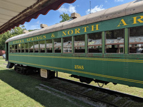 A vintage green train car labeled "Eureka Springs & North Arkansas" parked on a railway track.