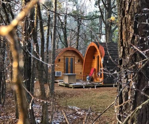 Two wooden cabins nestled in a forest, surrounded by trees, with a small deck and outdoor seating.