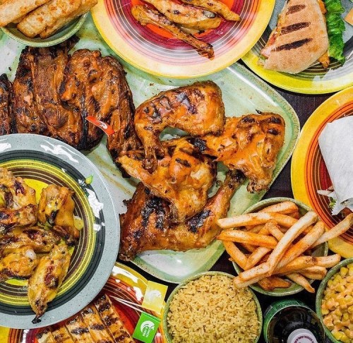 A colorful spread of grilled meats, rice, fries, and tortillas on vibrant plates, showcasing a delicious feast.