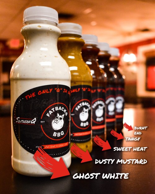 Five bottles of Fatback's BBQ sauces in various flavors, labeled with descriptions like "Sweet Heat" and "Dusty Mustard."
