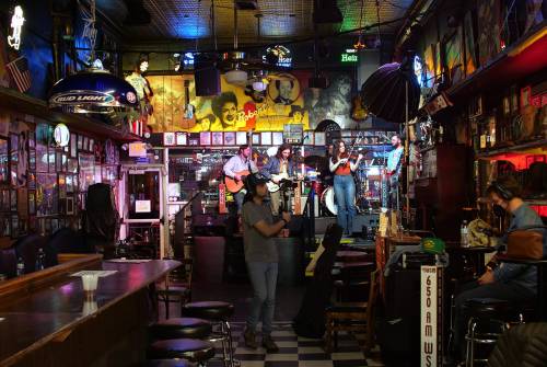 A lively bar scene with a band performing on stage, surrounded by colorful lights and vintage decor.