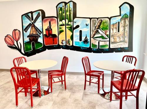 A colorful mural spelling "Holland" with red chairs and tables in a bright, modern café setting.