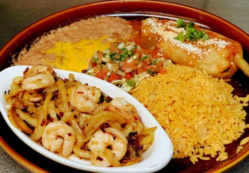 A plate of shrimp with onions, rice, refried beans, salsa, and a corn dog topped with cilantro.