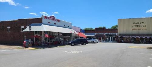 A small town street featuring shops, including a thrift store and an antique store, under a clear blue sky.