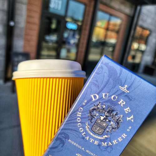 A yellow coffee cup next to a blue chocolate box from Ducrey Chocolate Maker in Missoula, Montana.
