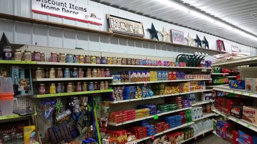 A store aisle filled with various discount items, including snacks, home decor, and colorful packaging on shelves.