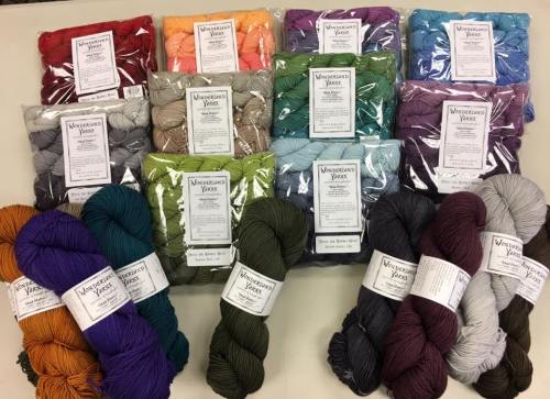 A variety of colorful yarn skeins and packs arranged neatly on a table, showcasing different shades and textures.