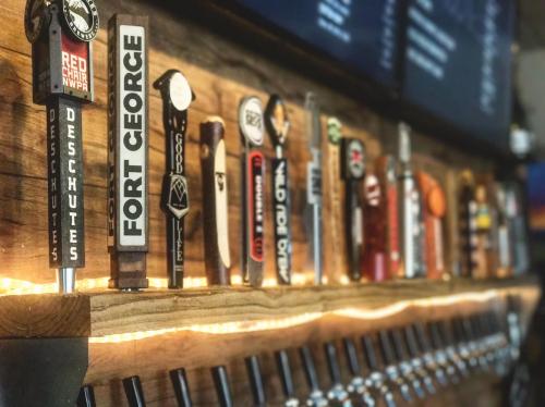 A wooden bar with various beer taps lined up, featuring labels from different breweries. Soft lighting enhances the scene.