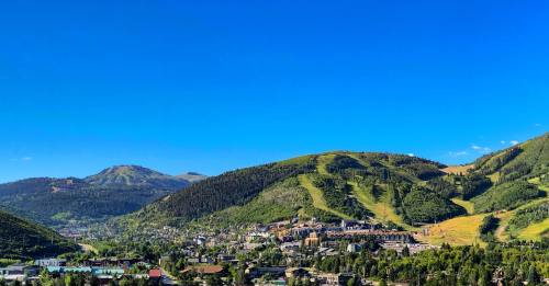 A scenic view of a mountainous landscape with a clear blue sky and a small town nestled in the valley below.