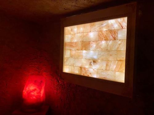 A glowing salt panel illuminated on a wall, with a red salt lamp beside it, creating a warm ambiance.