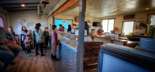 A cozy café interior with customers at the counter, children nearby, and a welcoming atmosphere.