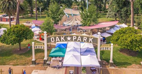 Aerial view of Oak Park entrance with tents and trees, showcasing a vibrant community space.