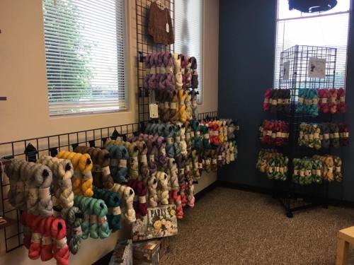 A cozy yarn shop display featuring colorful skeins of yarn arranged on walls and shelves.