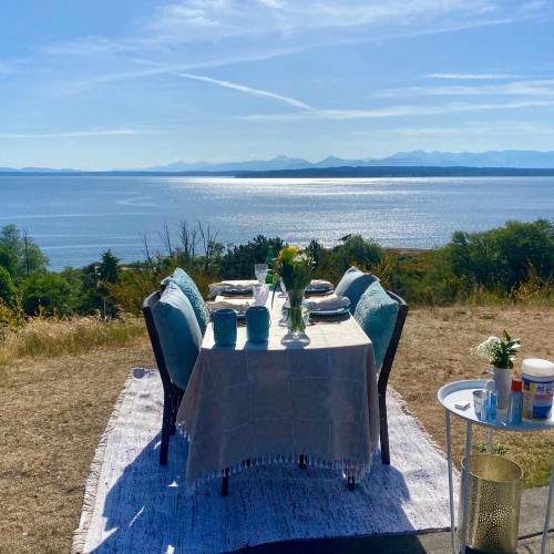 A beautifully set outdoor dining table overlooking a serene lake and mountains under a clear blue sky.
