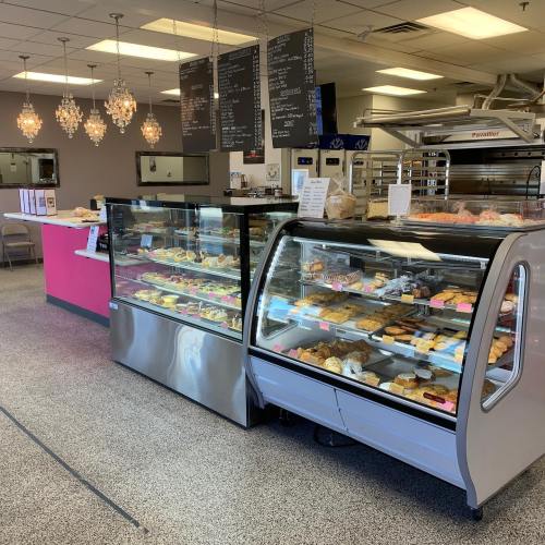 A bakery display case filled with various pastries and desserts, with a cozy seating area in the background.