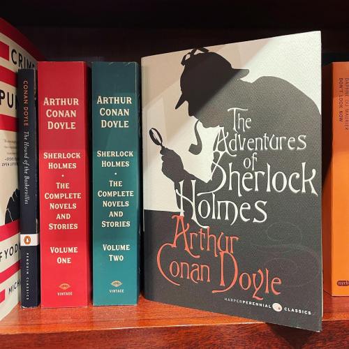 A bookshelf displaying "The Adventures of Sherlock Holmes" by Arthur Conan Doyle alongside other related books.