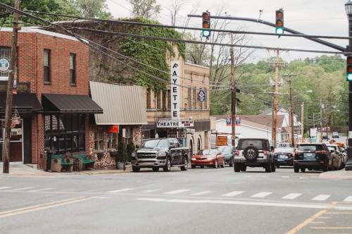 A street view of a small town featuring shops, a theater, and parked cars under a cloudy sky.