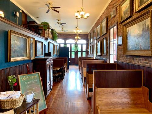 A cozy hallway with wooden benches, framed paintings, and a welcome sign, leading to a bright entrance.