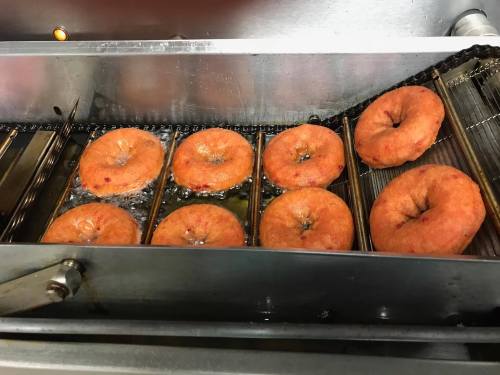 Freshly fried donuts cooking in a fryer, golden brown and bubbling in hot oil.