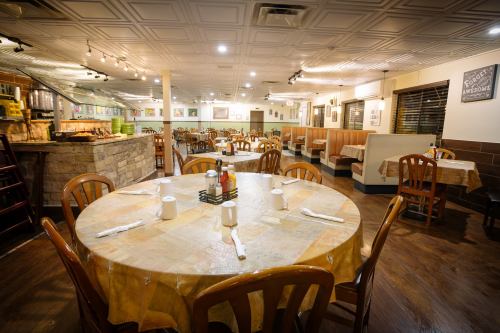 A spacious restaurant interior with wooden tables, chairs, and a cozy atmosphere, ready for diners.