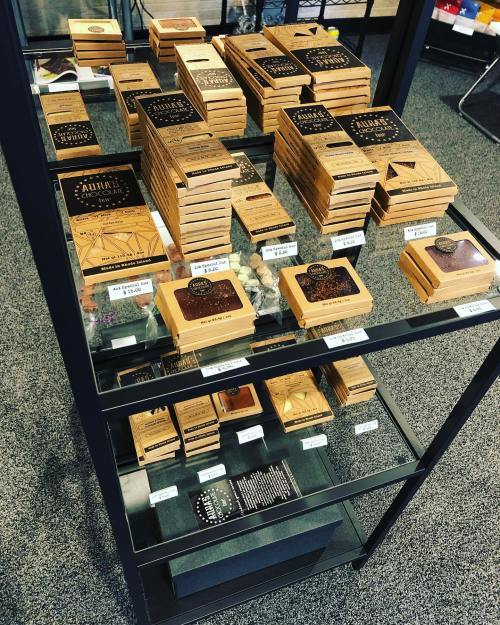 Display of various wooden boxes and products on a glass shelf, featuring intricate designs and labels.