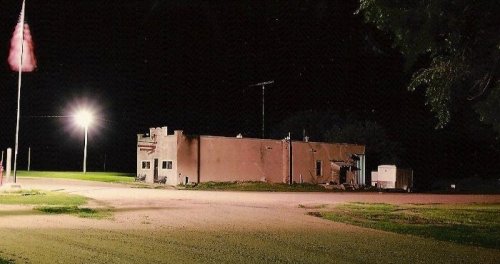 A dimly lit building at night, with a flag and a streetlight illuminating the surrounding area.