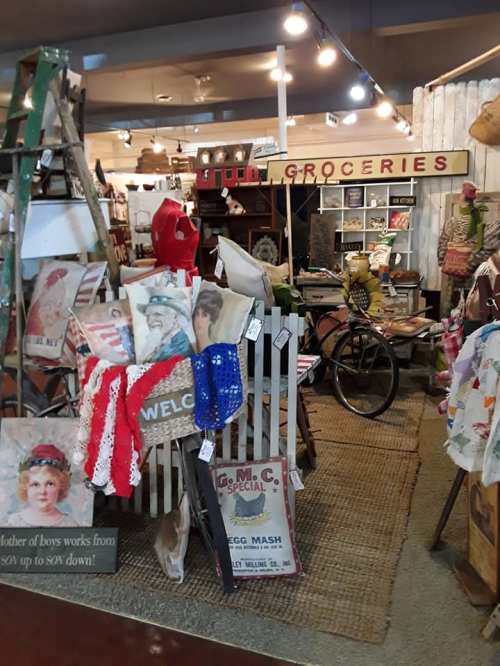 A vintage shop filled with eclectic items, including signs, a bicycle, and various antiques displayed on shelves.