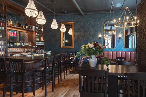 Elegant restaurant interior featuring chandeliers, a bar, and a floral centerpiece on a dark wooden table.