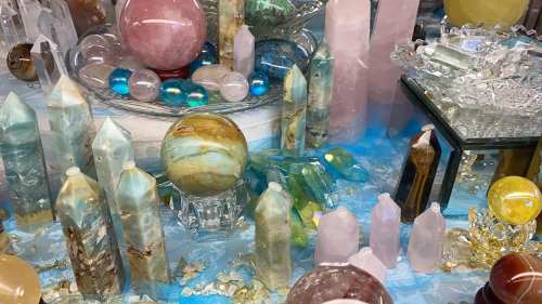 A colorful display of various crystals and gemstones, including polished spheres and pointed towers, on a blue surface.