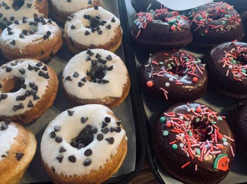 A tray of assorted donuts: some with white icing and chocolate chips, others with chocolate icing and colorful sprinkles.