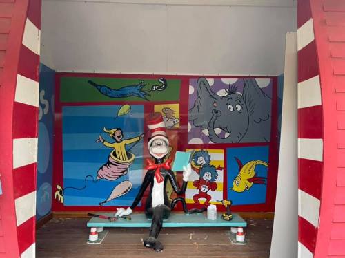 A whimsical display featuring the Cat in the Hat sitting on a bench, surrounded by colorful Dr. Seuss-themed murals.