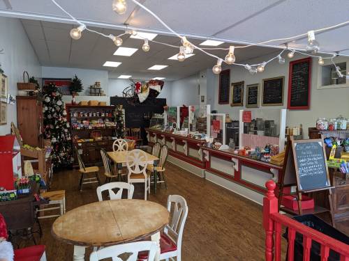 Cozy café interior decorated for the holidays, featuring a Christmas tree, seating, and a counter with treats.
