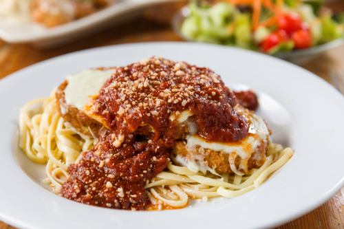 A plate of spaghetti topped with breaded chicken, marinara sauce, and cheese, served with a side salad.