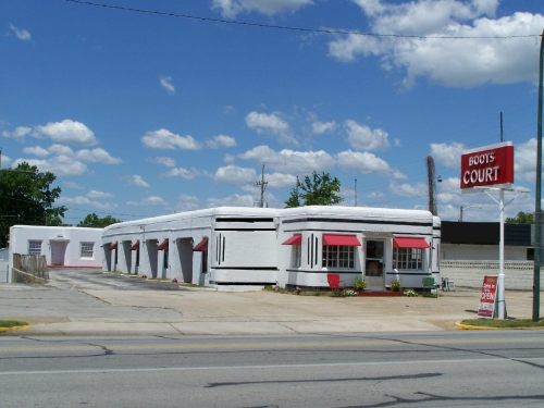 A retro-style white building with red accents, featuring large windows and a sign that reads "Boots Court."