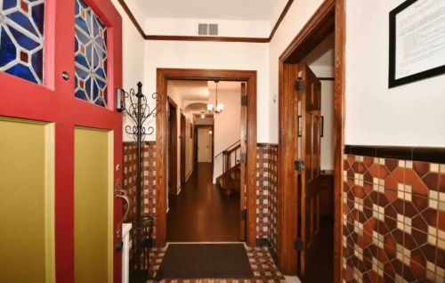 A colorful entryway with a red door, tiled walls, and a view of a hallway leading to rooms.