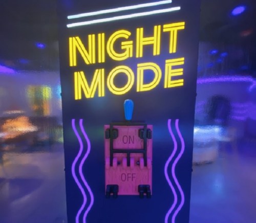 A brightly lit sign reading "NIGHT MODE" above a toggle switch with "ON" and "OFF" positions.
