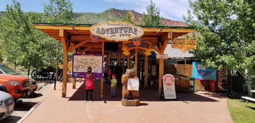 Entrance to Glenwood Caverns Adventure Park, featuring a wooden sign and visitors in a scenic outdoor setting.